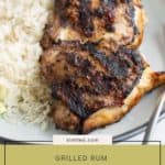 A plate featuring two pieces of succulent jerk chicken and a serving of white rice. Text overlay reads "Grilled Rum Jerk Chicken.
