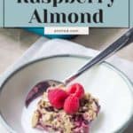 A bowl with a slice of baked oatmeal topped with raspberries and almonds, accompanied by a spoon. The text on the image reads "Baked Oatmeal Raspberry Almond," offering a wholesome twist akin to birthday cupcakes.