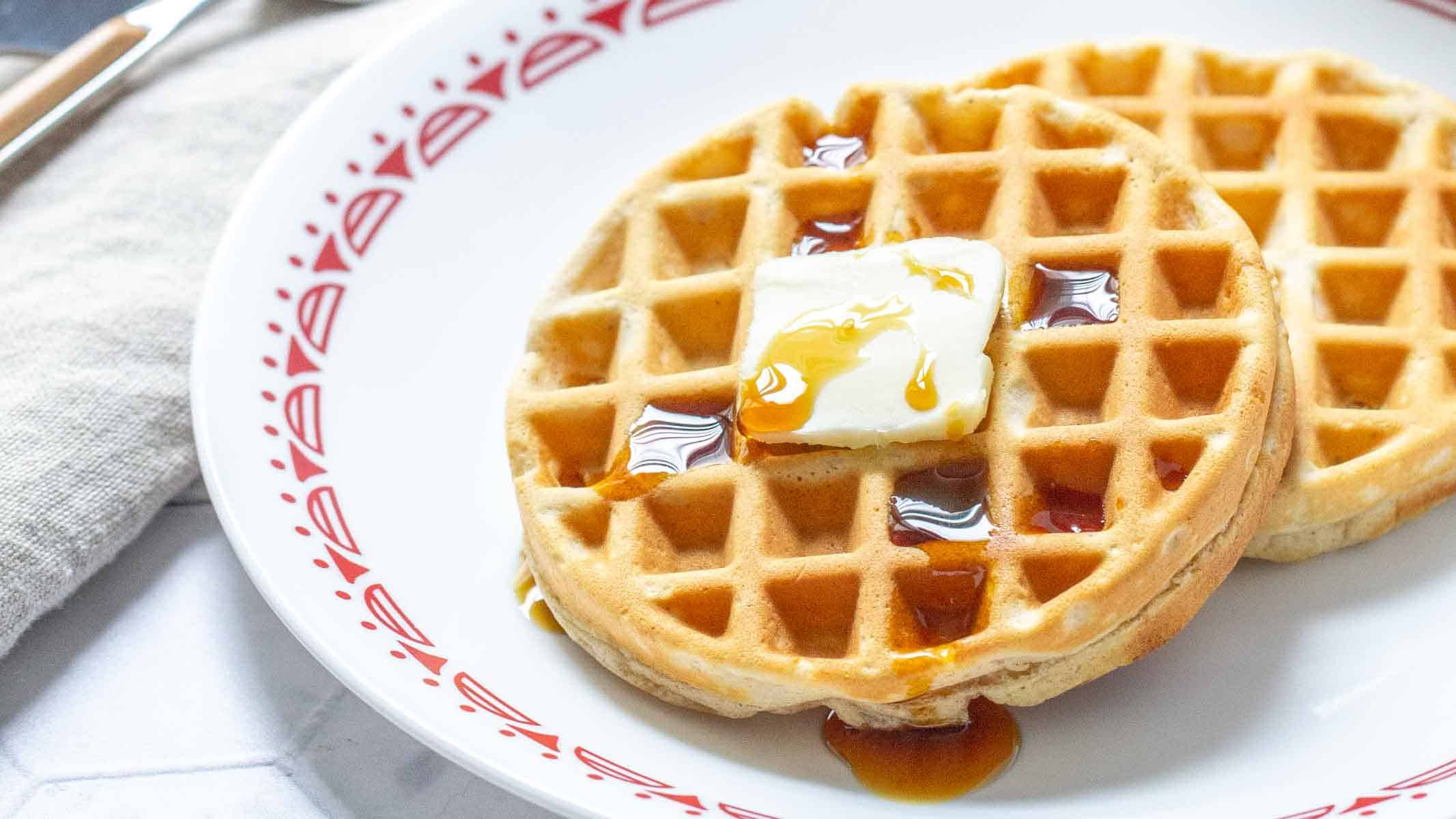 Peanut butter waffles with butter and syrup on a plate.