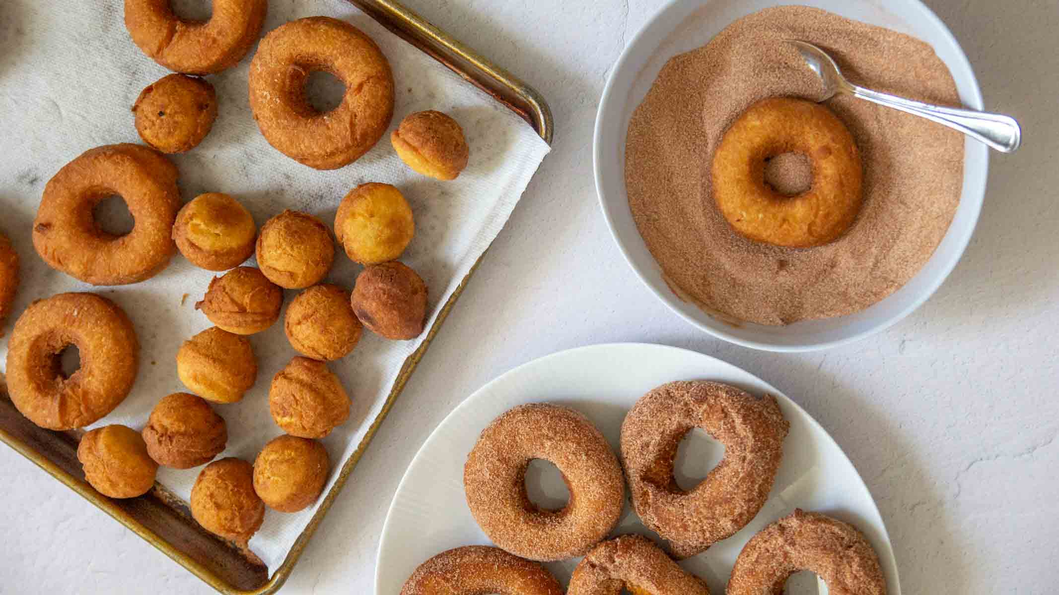 Pumpkin donuts being dipped in cinnamon sugar.