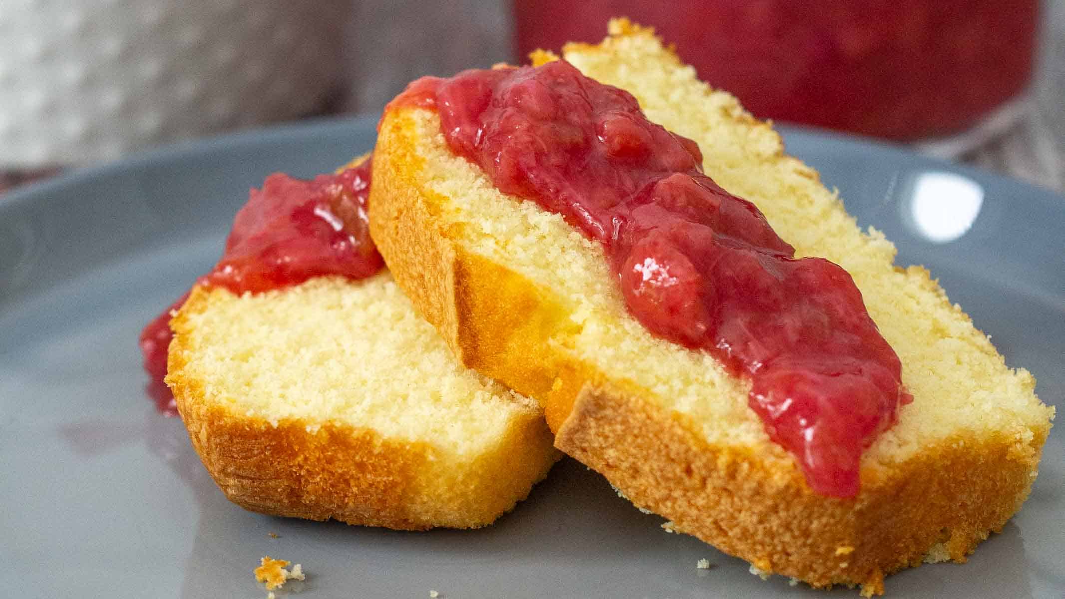 Two slices of pound cake topped with strawberry rhubarb sauce on a gray plate.
