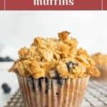 A blueberry streusel muffin in a paper liner sits on a cooling rack, with streusel topping and visible blueberries. Text at the top reads "blueberry streusel muffins.