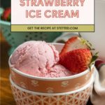 Two scoops of strawberry ice cream in a patterned bowl, garnished with fresh strawberries. A sign above reads "Strawberry Ice Cream" and "Get the recipe at stetted.com.