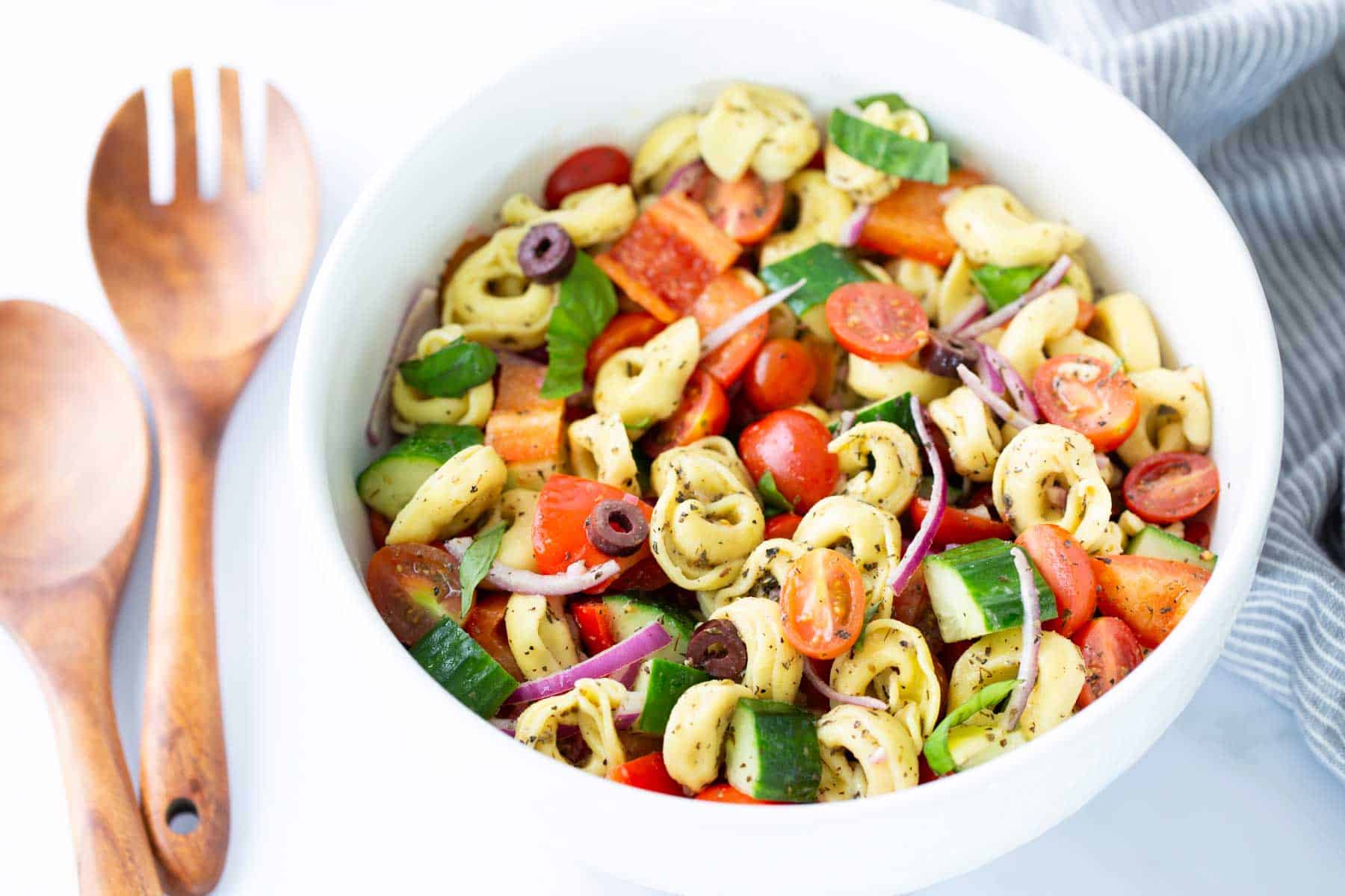 A serving bowl filled with tortellini pasta salad.