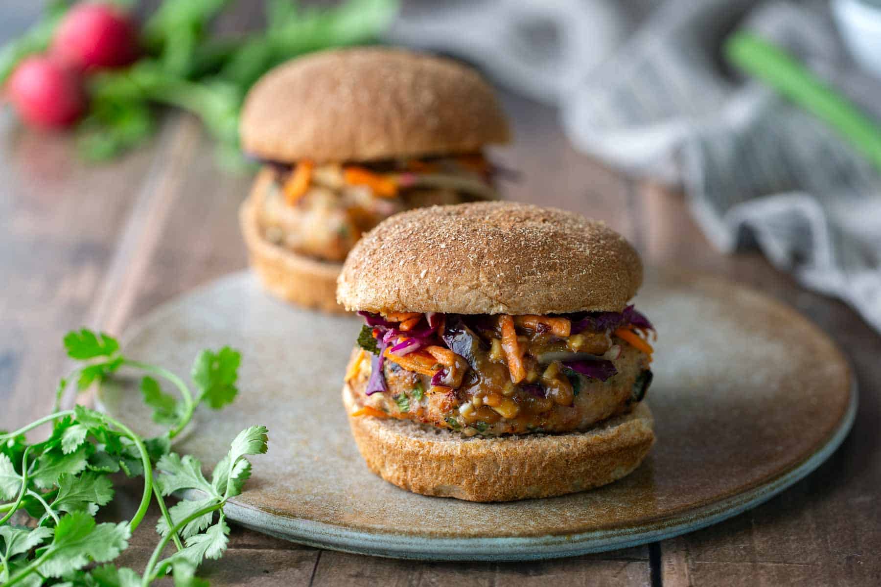 A chicken burger with slaw and peanut sauce on a plate.