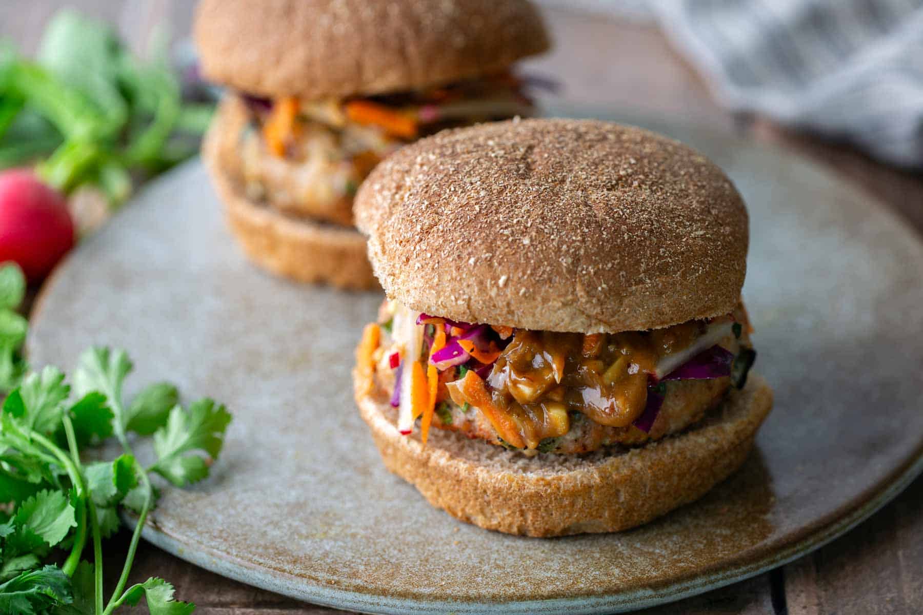 Two peanut chicken burgers on a serving platter.