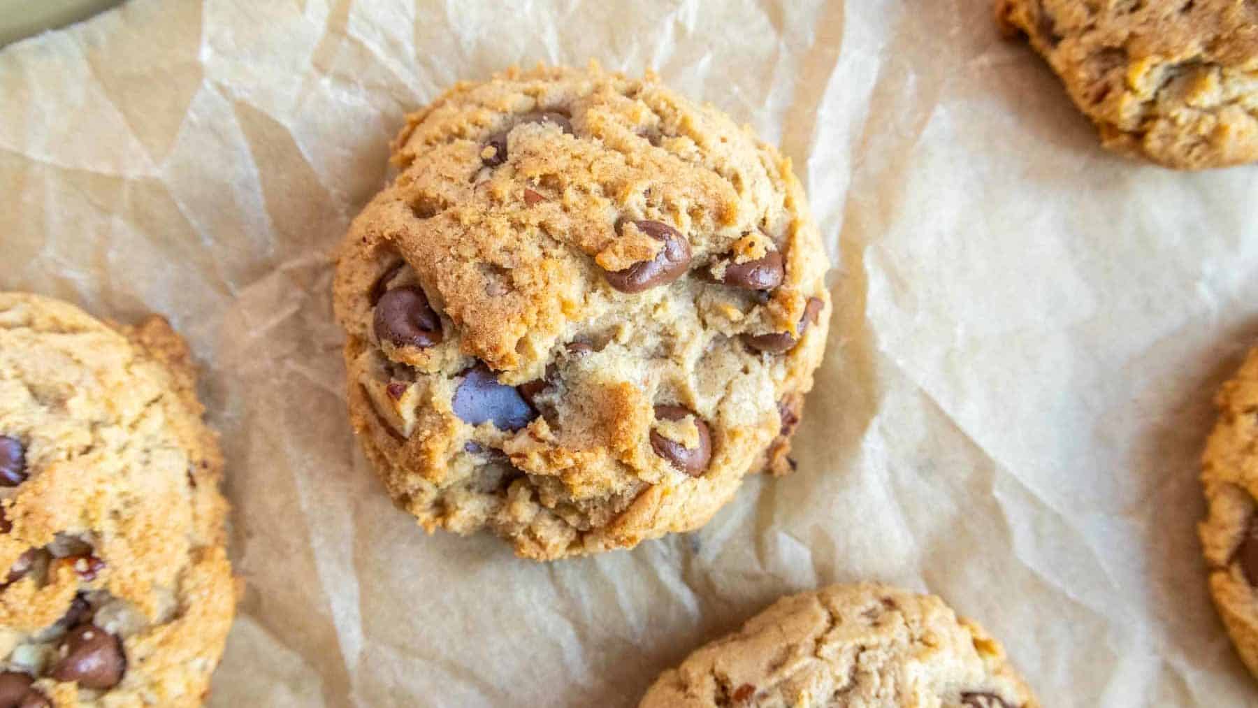 Three chocolate chip cookies on parchment paper.