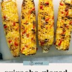Four grilled corn cobs are topped with sriracha glaze, arranged side by side on a light-colored surface.