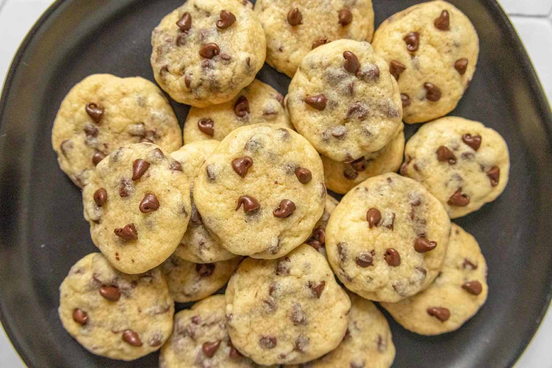 A plate filled with several chocolate chip cookies, arranged in an overlapping pile.