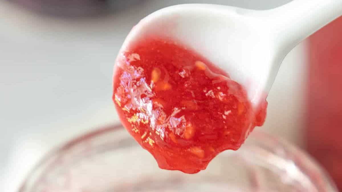 Raspberry jam in a jar with a spoon.
