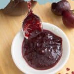 Bowl of cherry BBQ sauce with a spoon, next to fresh cherries on a wooden surface. Text reads "Cherry BBQ Sauce" and "stetted.com.