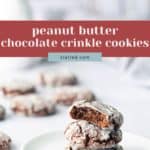 A stack of three peanut butter chocolate crinkle cookies sits on a white plate, with more cookies blurred in the background.