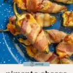Bacon-wrapped jalapeño poppers filled with pimento cheese, arranged on a blue plate.