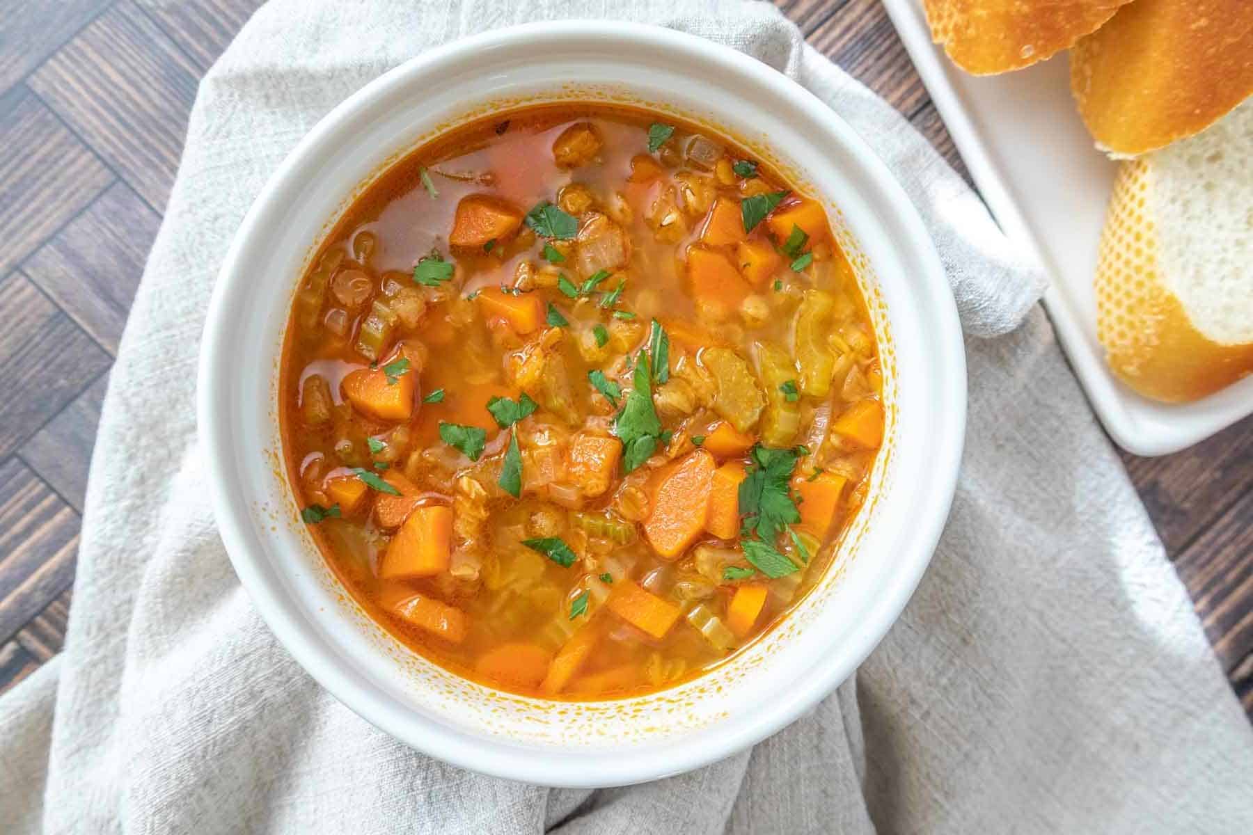 White bowl of red lentil soup with a tan napkin underneath.