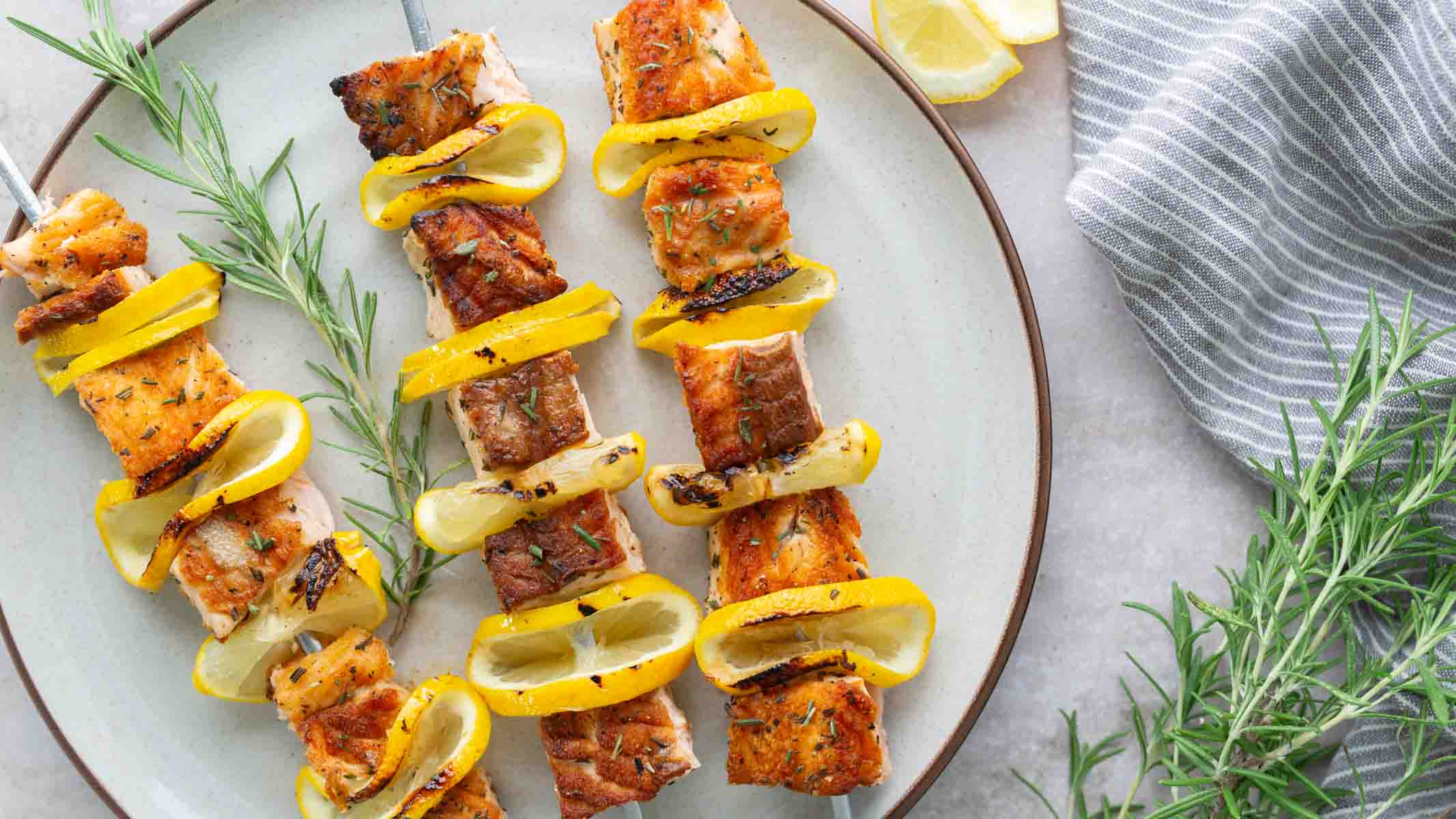 Salmon skewers with lemon on a plate.