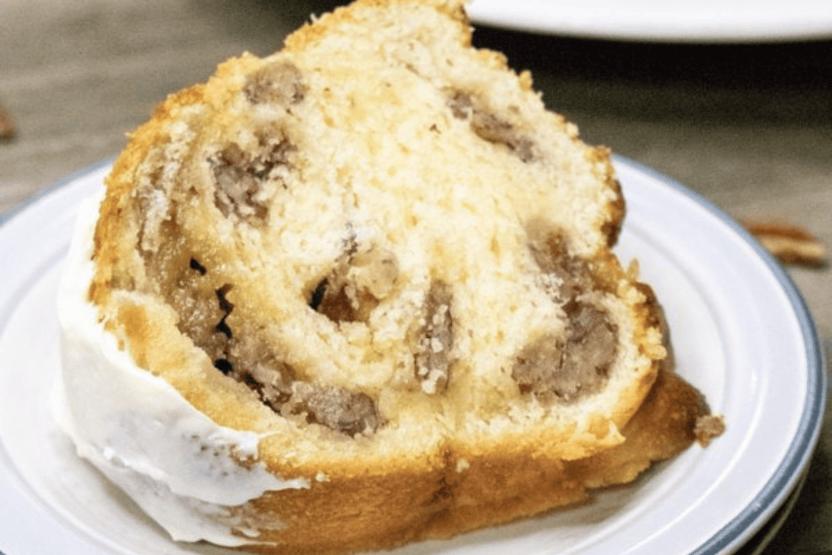 A slice of bundt cake with a cinnamon swirl and icing on a white plate.