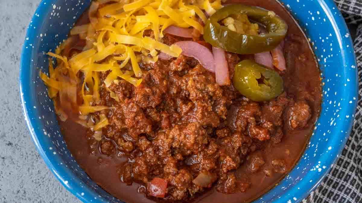 Bowl of bison chili with shredded cheese and jalapeños on top.
