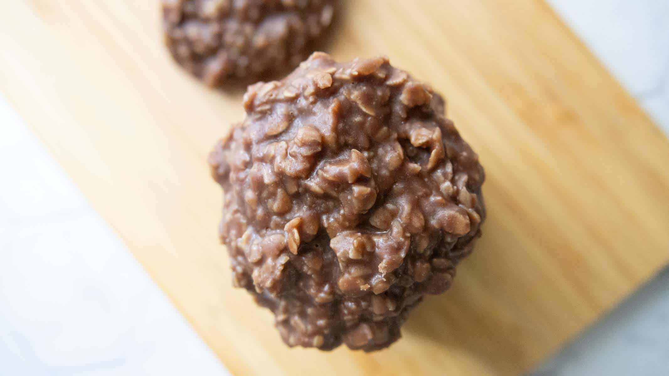A close-up of a chocolate no-bake cookie with oats on a wooden surface.