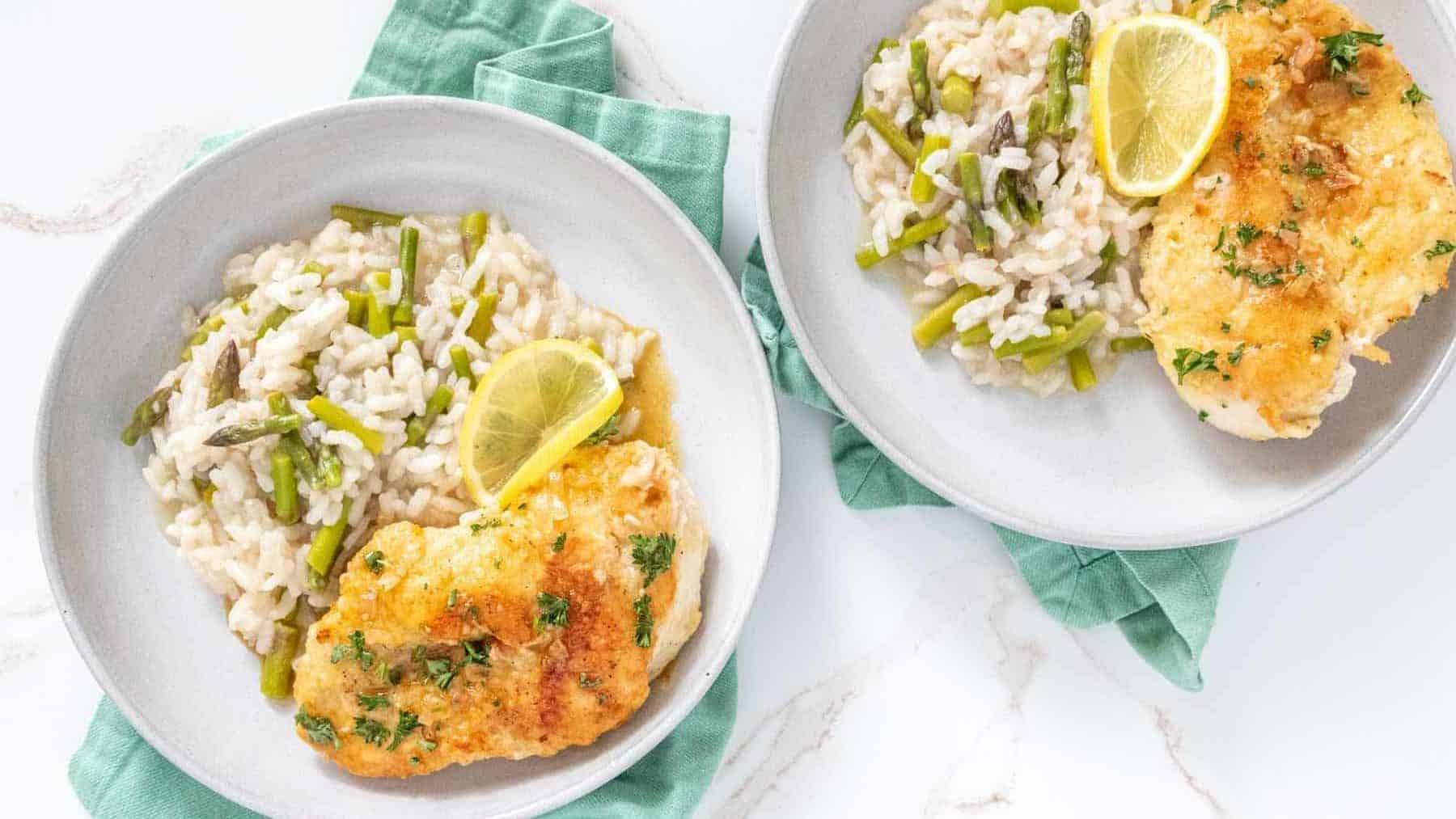Overhead of lemon chicken and asparagus risotto on plates.