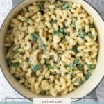 A pot of cavatappi pasta mixed with lemon ricotta sauce and spinach, viewed from above on a light countertop.