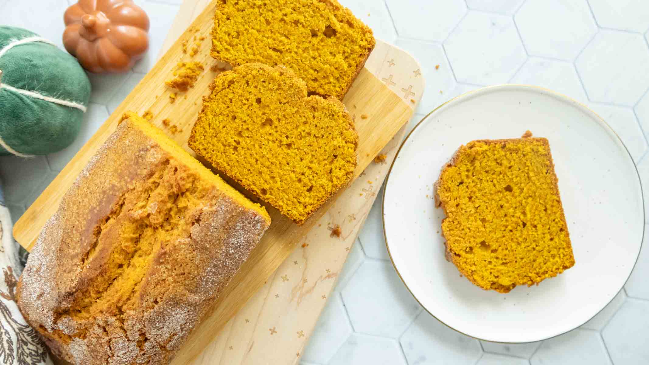 Sliced pumpkin bread on a cutting board with one piece on a plate.