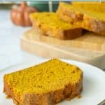 A slice of pumpkin bread on a white plate with more slices on a wooden board in the background; text reads "pumpkin bread.
