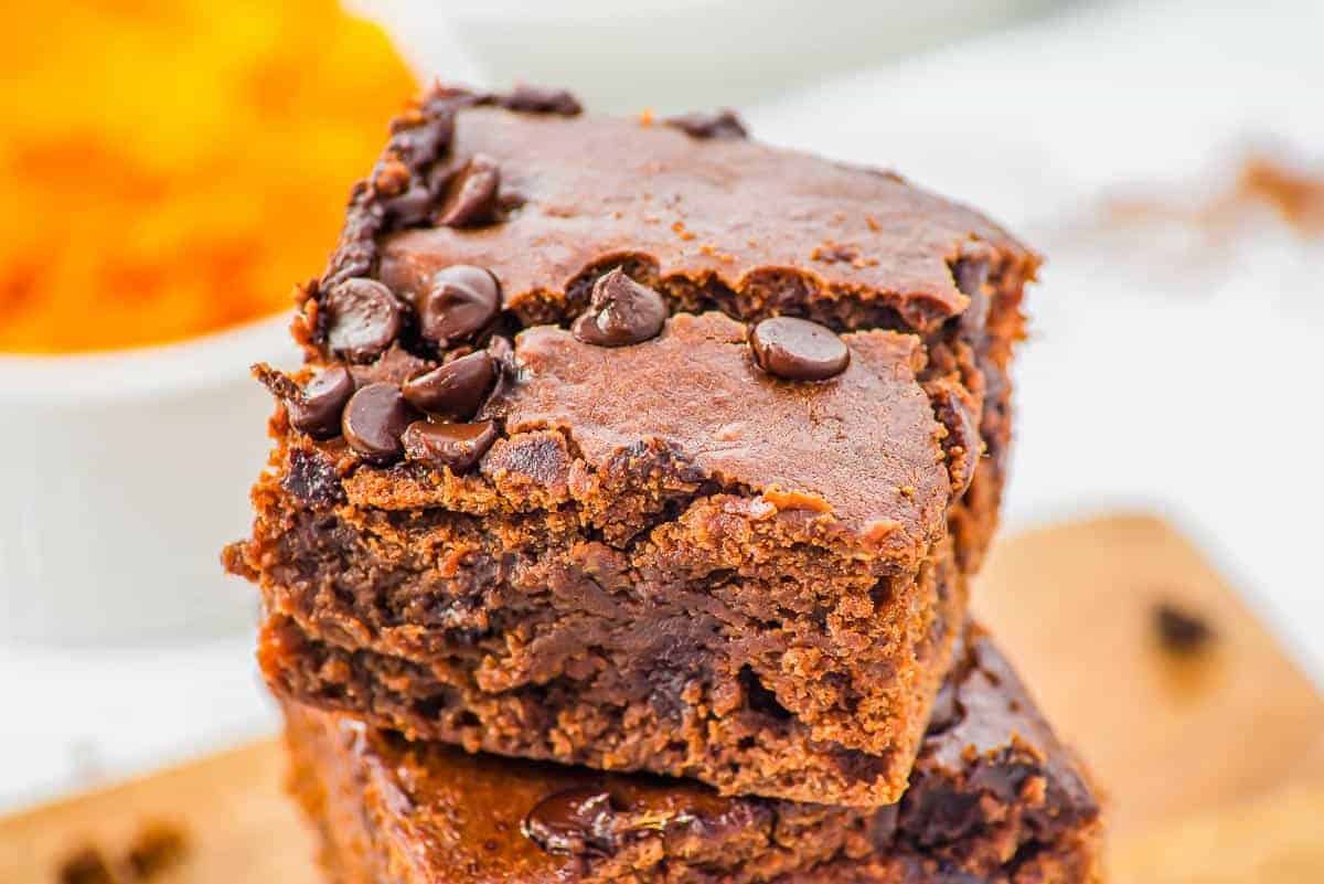 Close-up of two stacked chocolate brownies topped with chocolate chips, showing a moist and dense texture.