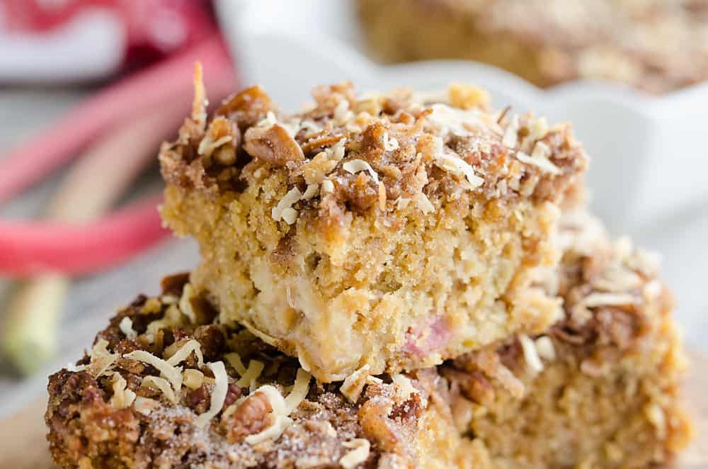 Two pieces of crumb-topped cake with visible nuts and shredded coconut are stacked on a plate.