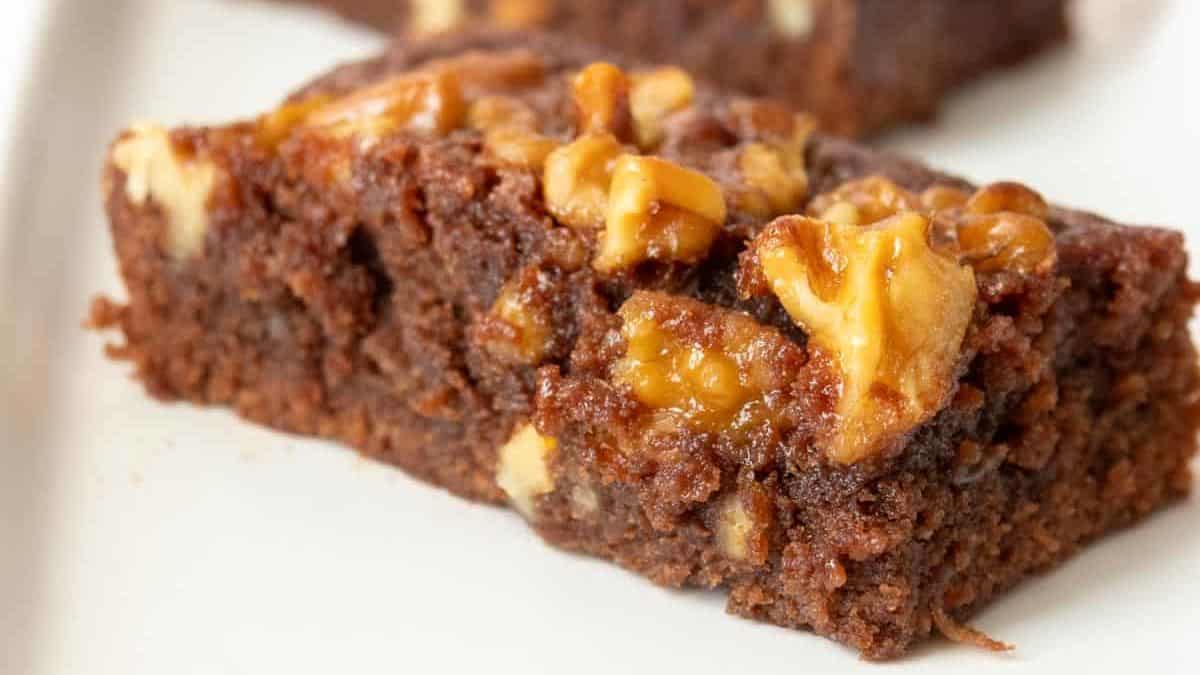 Two brownies with walnuts on a white plate.