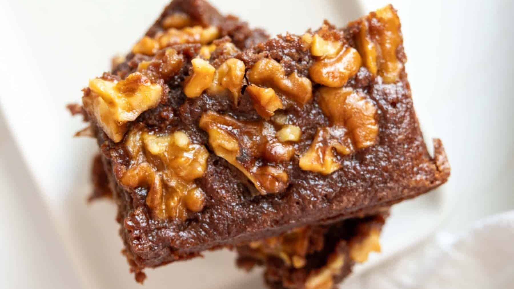 A stack of brownies with walnuts on a white plate.