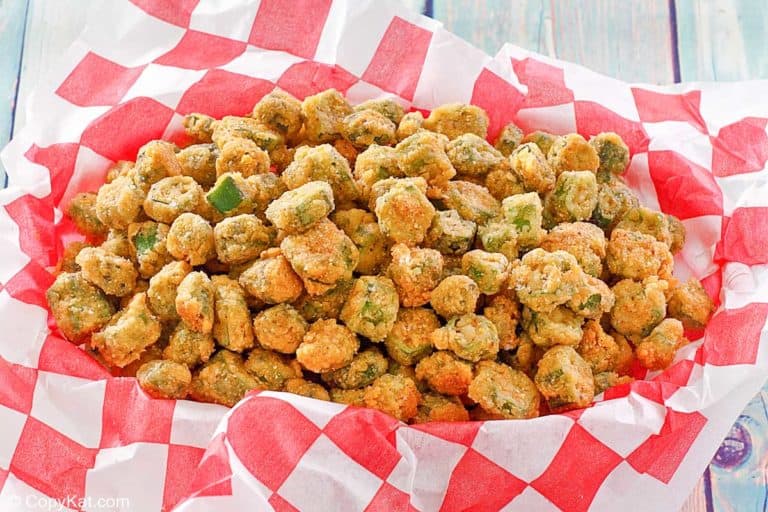 A basket lined with red and white checkered paper filled with fried okra pieces.
