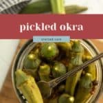 A jar of pickled okra with a fork inside sits on a wooden board; fresh okra and a checked cloth are in the background. Text reads "pickled okra" and "stetted.com.