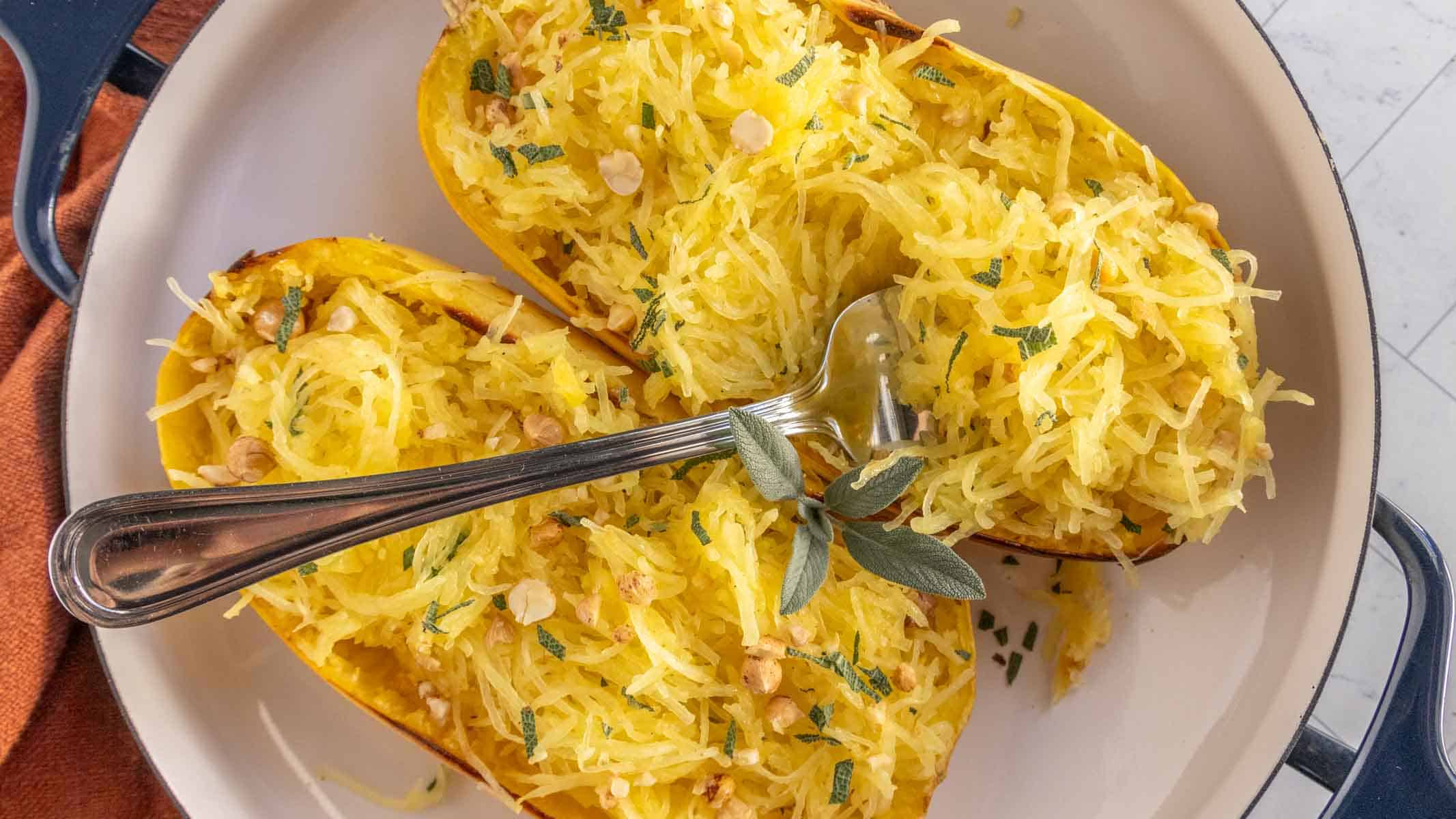 A dish with two spaghetti squash halves and a serving fork.