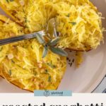 A plate with roasted spaghetti squash halves topped with chopped sage and nuts, with a fork separating the squash strands.
