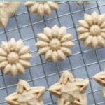 Flower and star-shaped spiced spritz cookies arranged on a wire cooling rack.