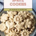 A bowl filled with various flower and star-shaped spritz cookies, with a label reading "Spritz Cookies" and a recipe link at the top.