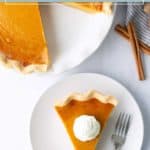 A slice of sweet potato pie with whipped cream on a plate next to a fork, with the remaining pie and cinnamon sticks nearby.