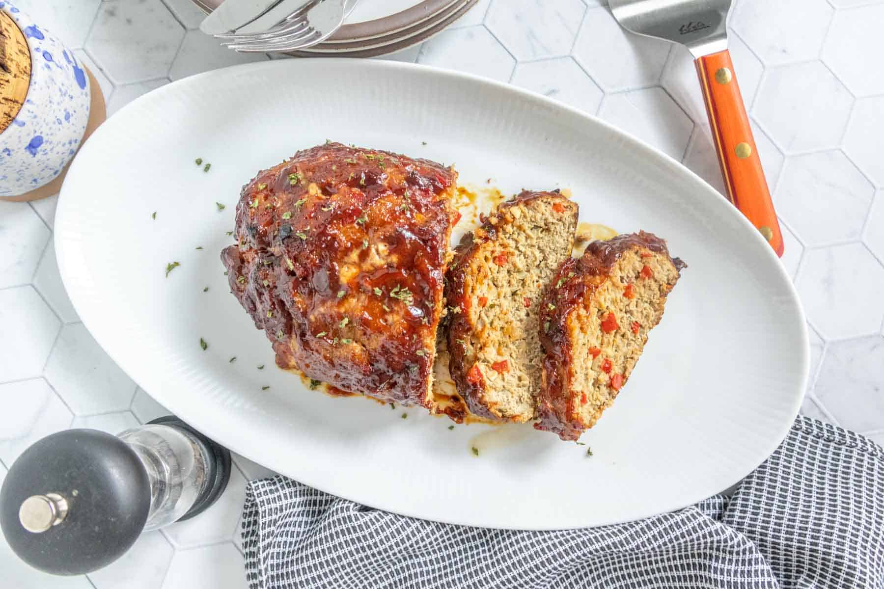 A white platter with a turkey meatloaf on it and two slices.