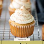 A chai cupcake with swirled frosting and a sprinkle of spice sits on a cooling rack. The text "chai cupcakes" appears at the bottom of the image.
