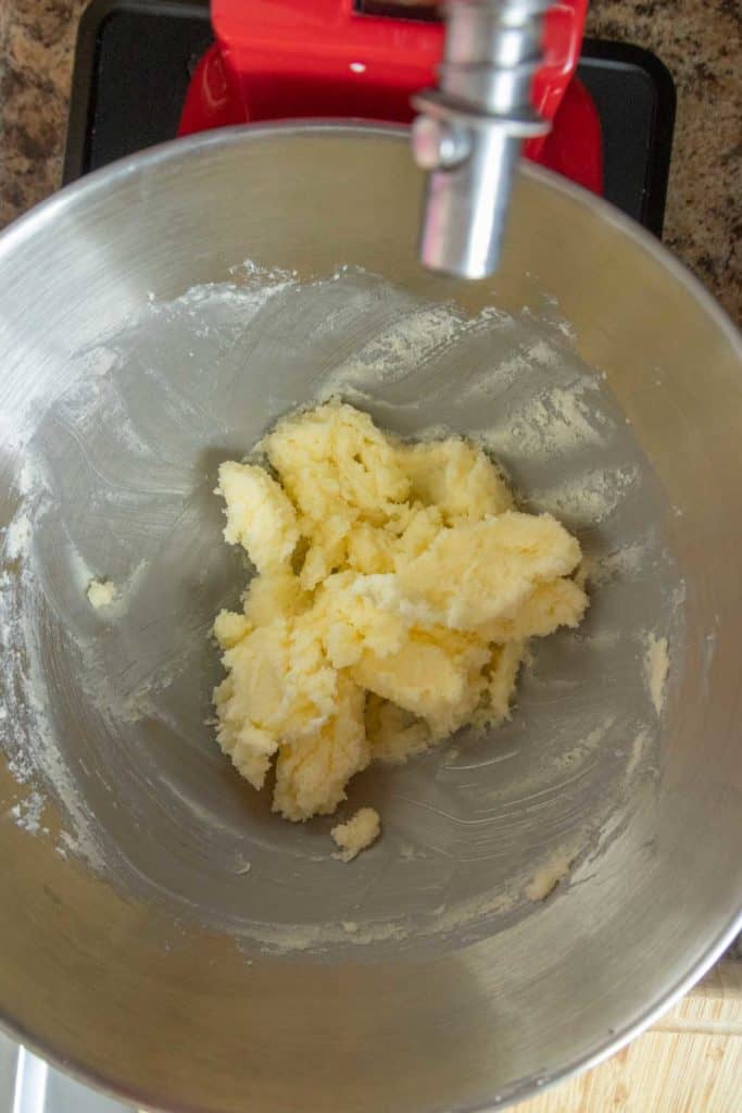 Stand mixer bowl with creamed butter and sugar mixture inside, viewed from above, on a kitchen countertop.
