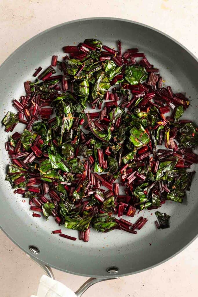 Sautéed beet greens and stems in a gray skillet.