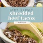 A dish of shredded beef with serving utensils, sliced avocados, and two shredded beef tacos on tortillas, topped with avocado slices and cheese.