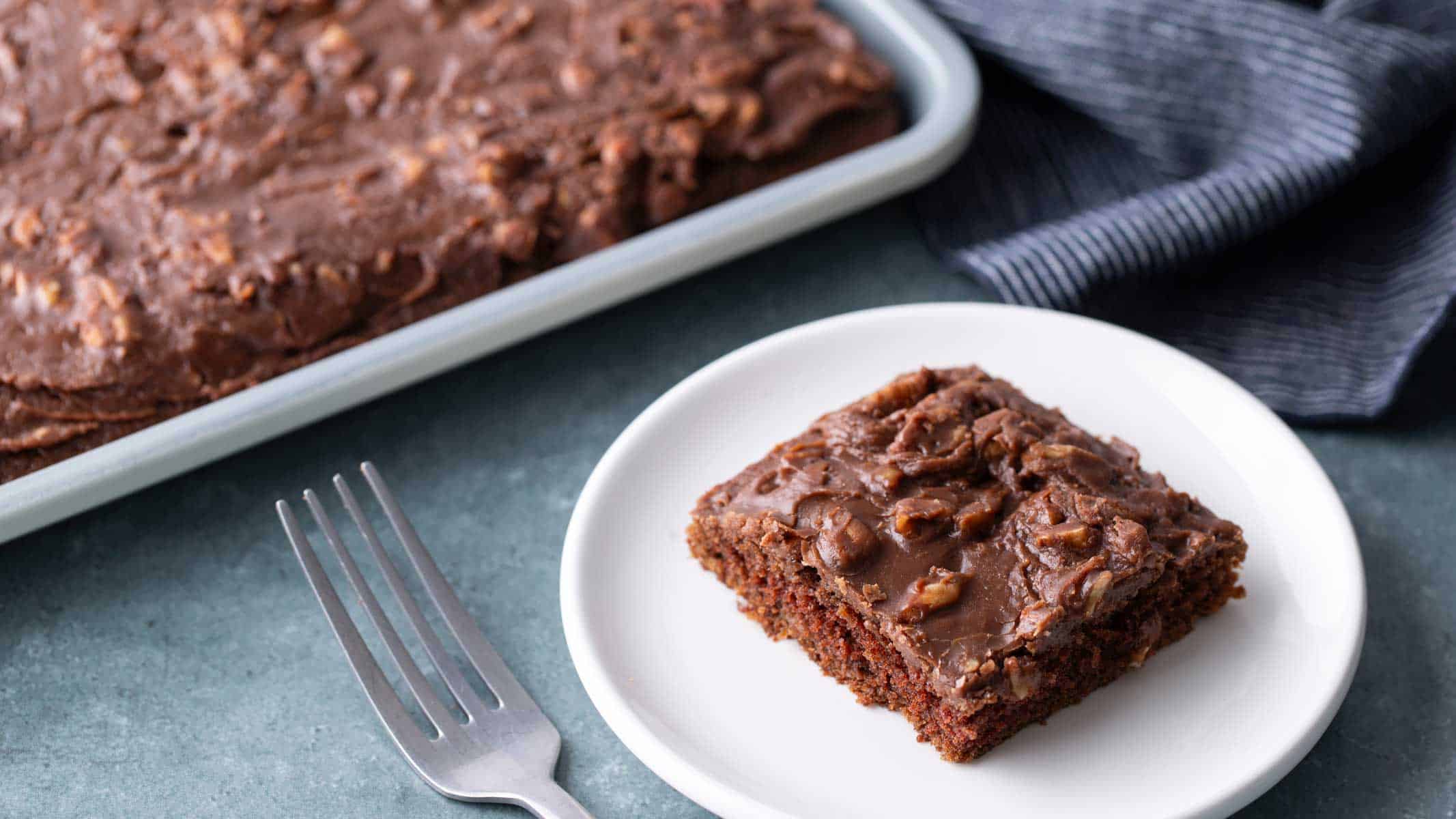 A slice of Texas sheet cake next to the rest of the cake in the pan.
