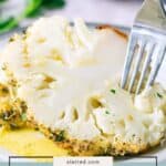 Close-up of a thick slice of whole roasted cauliflower on a plate, being cut with a fork, with herbs and sauce visible. Text at the bottom reads "whole roasted cauliflower.