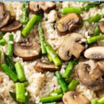 Close-up of asparagus and mushroom risotto, showing sliced mushrooms, asparagus pieces, and creamy rice.