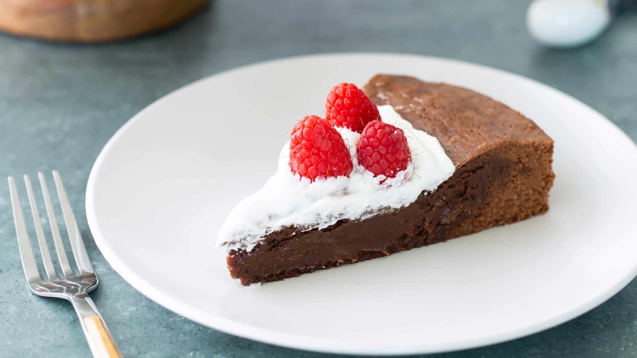 A slice of Swedish chocolate cake on a plate, topped with whipped cream and berries.