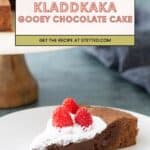 A slice of chocolate cake topped with whipped cream and raspberries on a white plate, with the rest of the cake visible in the background.