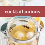 A glass jar filled with cocktail onions and peppercorns in brine, with martini glasses garnished with cocktail onions in the background.