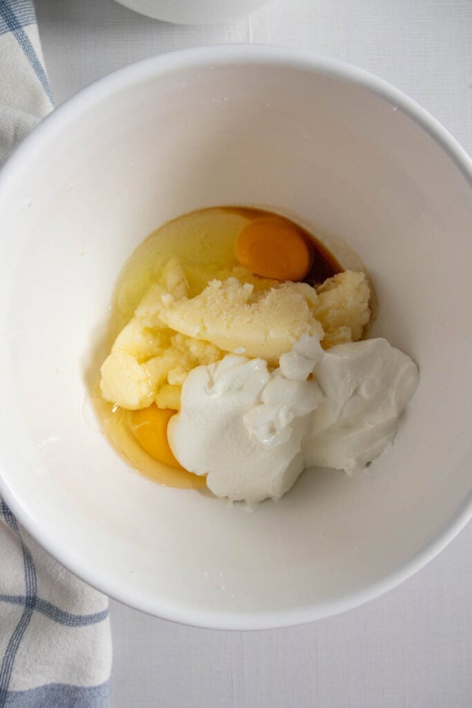 A white bowl containing eggs, butter, and sour cream.