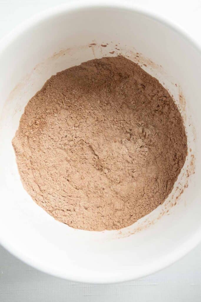 A white bowl filled with a mixture of flour and cocoa powder.